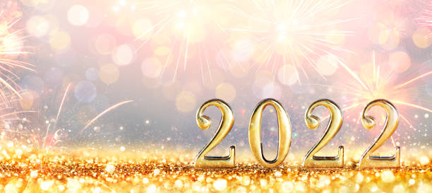2022 New Year Celebration - Golden Numbers On Glitter With Fireworks And Defocused Background stock photo