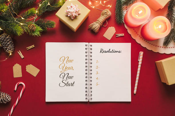 New year resolution notebook with checklist of goals and Christmas stuff on red background. Blank paper, new start concept. stock photo