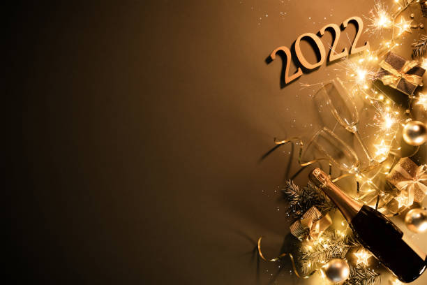 New Years Eve holiday background with fir branches, number 2022, champagne bottle, christmas balls, gift box and lights stock photo