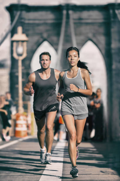 new york city runners athletes training jogging on brooklyn bridge for marathon race, fit couple on outdoor summer run jog. vertical background - brooklyn marathon 個照片及圖片檔