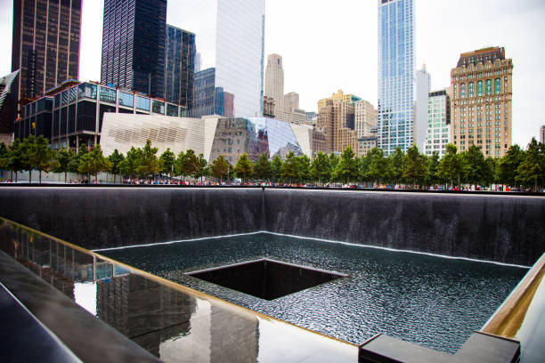 New York City World Trade Center in downtown New York, United States - August 22, 2014: National September 9/11 memorial waterfalls with surrounding buildings in Lower Manhattan. 911 memorial stock pictures, royalty-free photos & images