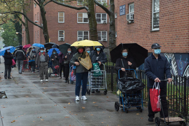 New York during the COVID-19 emergency. Queens, New York. October 28, 2020. A large crowd of people wait in line outside an outdoor food pantry in Woodside organized by "Sunnyside Community Services" food bank stock pictures, royalty-free photos & images