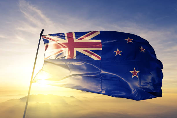 New Zealand Zealander flag textile cloth fabric waving on the top sunrise mist fog stock photo