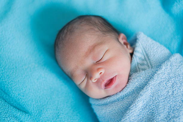 Newborn baby Asia  while sleeping covered with blue cloth stock photo