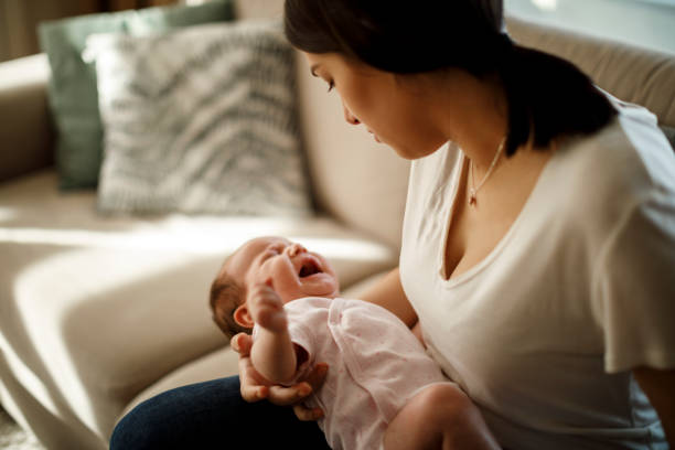 新生児は母の手で泣いている - 赤ちゃん　心配 ストックフォトと画像