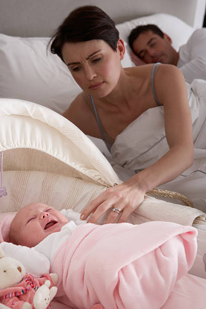 newborn baby crying in parents bedroom - wiegman stockfoto's en -beelden