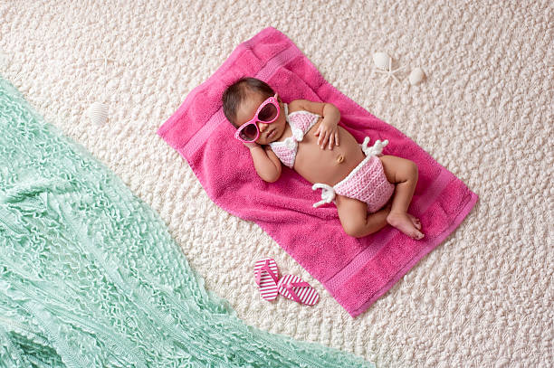 Newborn Baby Girl Wearing a Bikini and Sunglasses Four week old newborn baby girl sleeping on a pink towel. She is wearing a crocheted pink and white bikini and pink sunglasses. Shot in the studio with props made to look as if she's at a beach. hot latino girl stock pictures, royalty-free photos & images