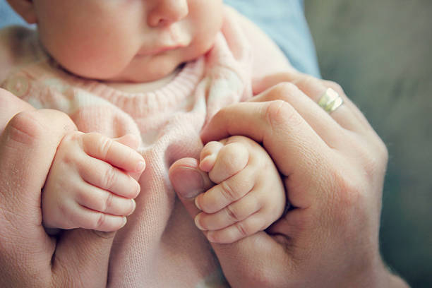 Newborn Baby Girls Hands Holding Fathers Fingers stock photo