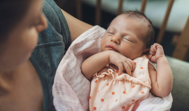 Newborn baby sleeping in safety while mother is holding and smiling at her stock photo