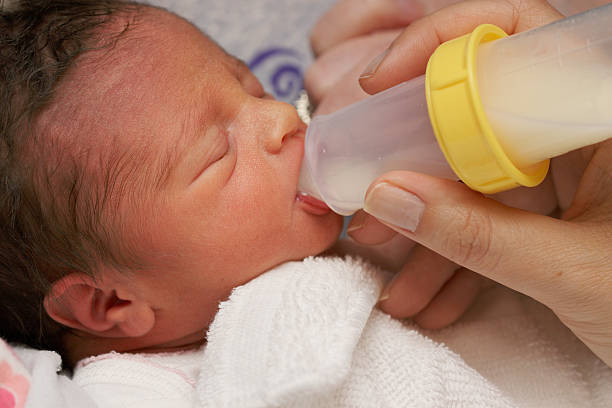 Newborn Preemie with Bottle "Newborn premature baby girl, just two days old, learning how to take a bottle with breastmilk." increase breast milk stock pictures, royalty-free photos & images