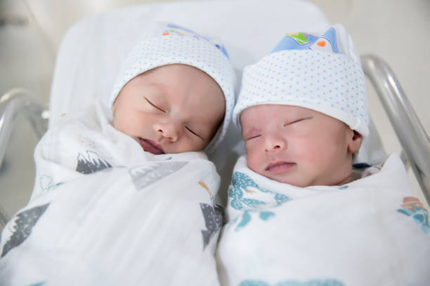 gemelos recién nacidos durmiendo. recién nacidos los bebés gemelos sueño en bed.lovely sueño de los bebés recién nacidos en la cama. - twins fotografías e imágenes de stock