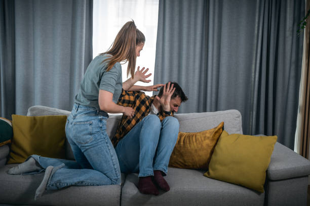 Newly married young couple where a woman attacks and mentally abuses her young husband due to sick jealousy and possessiveness and he suffers from domestic violence trying to defend himself stock photo
