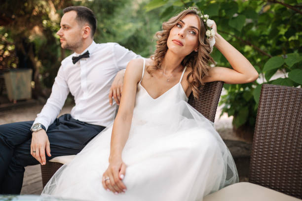 Newlywed coupe sitting on a sofa angry at each other in a middle of an argument. Young couple problem concept outdoor Newlywed coupe sitting on a sofa angry at each other in a middle of an argument. Young couple problem concept outdoor. bride stock pictures, royalty-free photos & images