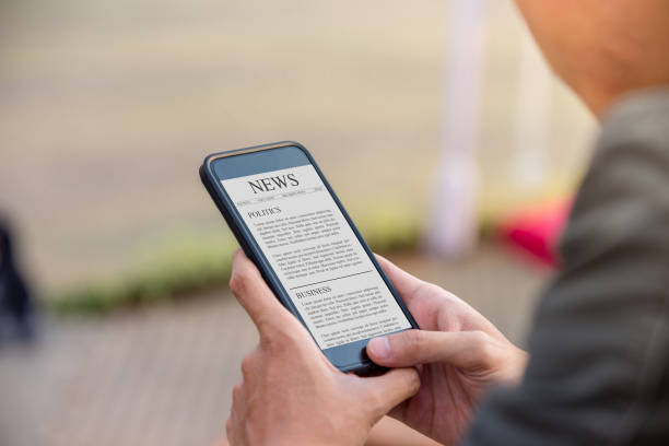 News article concept on phone screen. Man holding smartphone reading news article on screen. stock photo