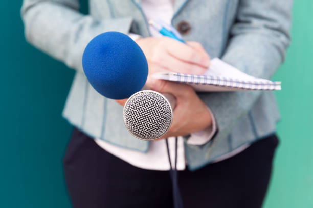 News reporter or TV journalist at press conference, holding microphone and writing notes News reporter or TV journalist at press conference, holding microphone and writing notes journalism stock pictures, royalty-free photos & images