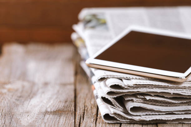 Newspaper and digital tablet Newspaper and digital tablet on wooden table article stock pictures, royalty-free photos & images