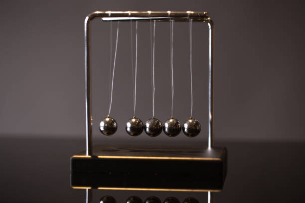 Newton cradle representing momentum Closeup metal Newton cradle placed on gray background as representation of momentum concept isaac newton picture stock pictures, royalty-free photos & images