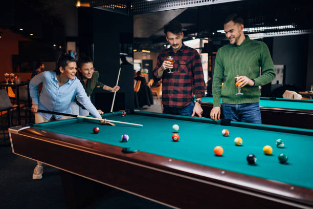 Nice shot! A group of smiling young people at the local pub. They play billiards, drink beer and hang out. stock photo