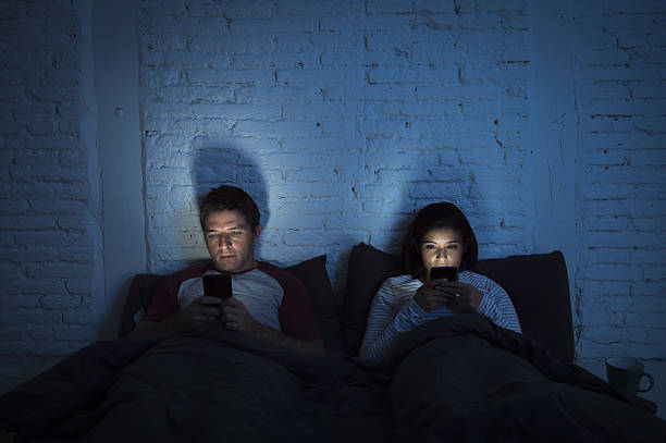 night couple in bed using mobile phone relationship communication problem stock photo