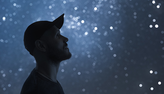 Night portrait. A man in profile. Starry sky bokeh in background