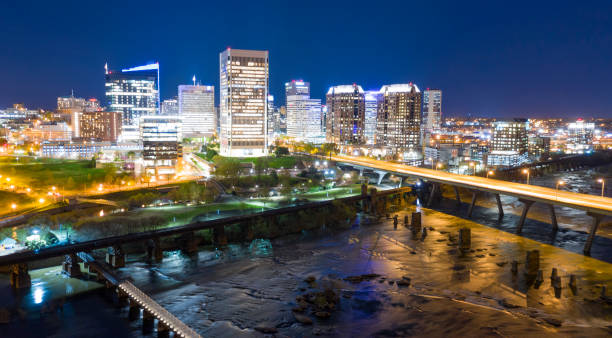 Night Scene Downtown City Skyline Riverfron Park Richmond Virginia Walkways vehicle traffic bridges and railroad trestles traverse the river in front of Richmond Virginia richmond virginia stock pictures, royalty-free photos & images