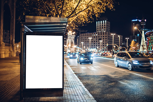 Night shot of a luminous advertising lightbox or display at a bus stop in Barcelona, Spain