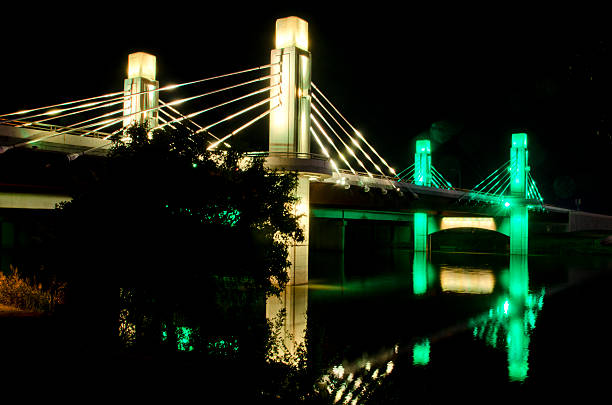 Night Shot of Pedestrian Bridge to McLane Stadium at Baylor One of two pedestrian bridges leading to McLane Stadium lit up in the Baylor colors of green and gold is reflected in the Brazos River.  McLane Stadium is the brand new football venue on the campus of Baylor University.  It stands on the banks of the Brazos River, providing the latest in sports and technology for unversity students and supporters, as well as an area along the river to provide "sail gating," where sailboats can tie off and celebrate the pregame atmosphere. baylor basketball stock pictures, royalty-free photos & images