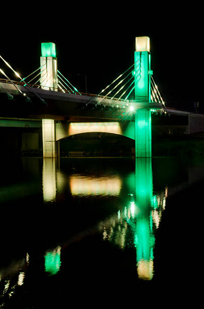 Night Shot of Pedestrian Bridge to McLane Stadium at Baylor One of two pedestrian bridges leading to McLane Stadium lit up in the Baylor colors of green and gold is reflected in the Brazos River.  McLane Stadium is the brand new football venue on the campus of Baylor University.  It stands on the banks of the Brazos River, providing the latest in sports and technology for unversity students and supporters, as well as an area along the river to provide "sail gating," where sailboats can tie off and celebrate the pregame atmosphere. baylor basketball stock pictures, royalty-free photos & images