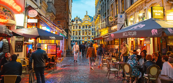 Brussels, Belgium - 22 June, 2022: Neon night street in Brussels old town, people resting in street cafe