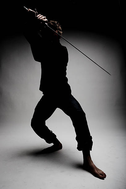 Ninja Parry Contemporary ninja in the shadows posing with sword. Canon 1Ds Mark 2 file bruce springsteen stock pictures, royalty-free photos & images