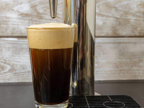 Nitro cold Brew Coffee in a clear glass on a dispenser stock photo