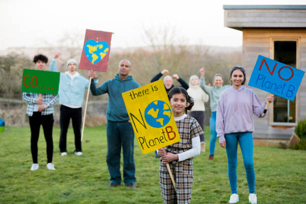 No Planet B A family standing on a grass area near their home holding signs with climate change messages on it, they are fighting the cause. They are looking at the camera  while standing in the North East of England. climate action stock pictures, royalty-free photos & images