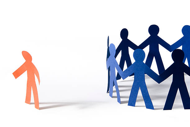 No, we don't want you! "Rejection hurts: Orange paper person with dejected stance off to the side of a circle of blue paper people. Isolated on white, with shadows.Similar photos:" prejudice stock pictures, royalty-free photos & images