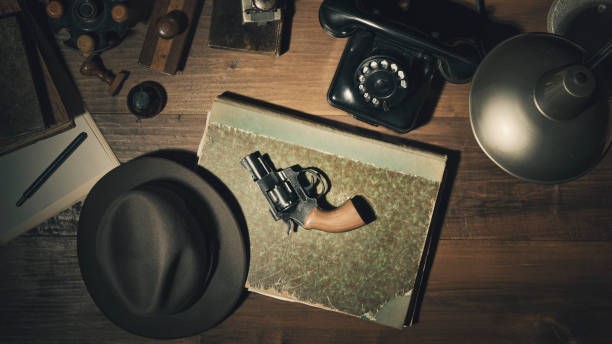 Noir 1950s style detective desktop with revolver Noir 1950s style detective vintage desktop with revolver, fedora hat and telephone, flat lay gangster stock pictures, royalty-free photos & images