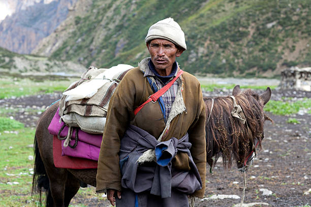 Nomadic people Shey, Nepal - September 4, 2011: Tibetan nomad with horse working walking on the road to Shey Gompa. tibetan ethnicity stock pictures, royalty-free photos & images