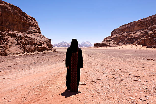 Nomadic woman with burka in the desert Nomadic woman dressed in Traditional burka standing alone in the the desert of jordan called "wadi rum", the measured temperature approximately 50 degree Celsius. hot middle eastern women stock pictures, royalty-free photos & images