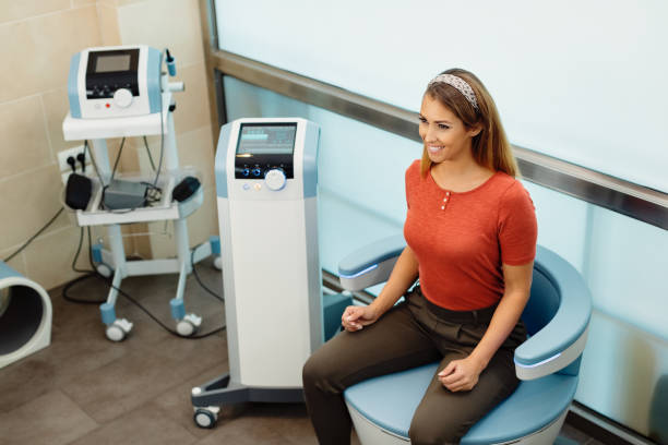 Non-invasive treatment for women's intimate health and wellness! Happy woman during electromagnetic procedure for urinary incontinence at medical clinic. pelvic floor stock pictures, royalty-free photos & images