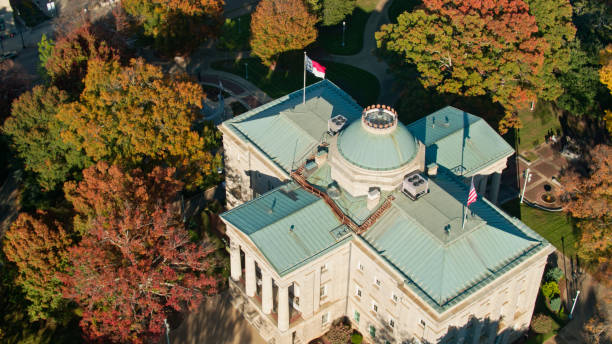 North Carolina and US Flags Flying Over State Capitol Building in Raleigh - Aerial Aerial shot of the North Carolina State Capitol Building in Raleigh on a sunny afternoon in Fall north carolina us state photos stock pictures, royalty-free photos & images