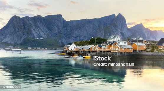 istock Norway, Lofotens, Sakrisoy village. Classic view of Lofoten Islands architecture - traditional wooden fishing houses rorbu at picturesque mountain peaks background during sunrise. 1278007951