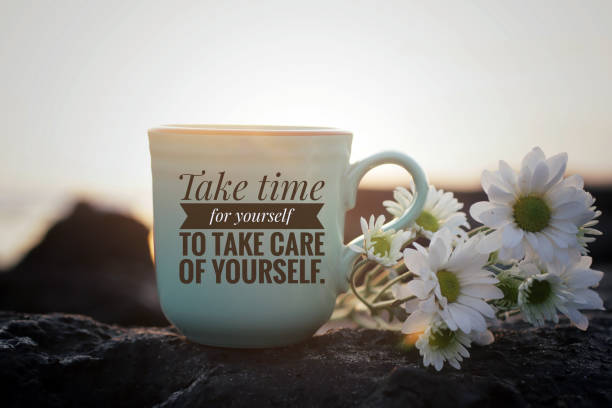 Note on a coffee cup - Take time for yourself to take care of yourself. Self love inspirational motivational words - Take time for yourself to take care of yourself. Written on a cup of morning tea or coffee with white daisy flowers on sea rock in the beach on background of sunset sunrise light. sunday morning coffee stock pictures, royalty-free photos & images