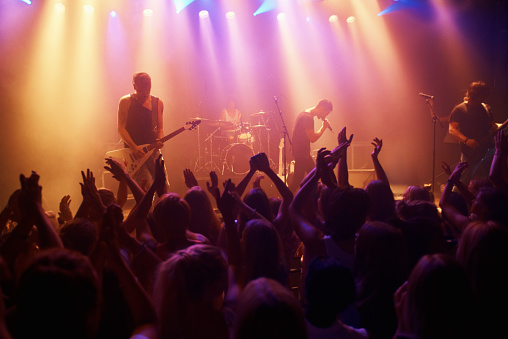 A band playing their hearts out at a festival show. This concert was created for the sole purpose of this photo shoot, featuring 300 models and 3 live bands. All people in this shoot are model released.