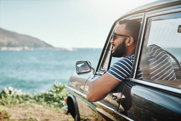 Nothing beats that edge of the world view Shot of a young man enjoying a road trip car lifestyle stock pictures, royalty-free photos & images