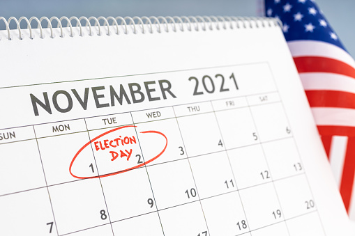 November 2021 USA election day concept. Desk calendar with November 2rd marked in red and USA flag at background