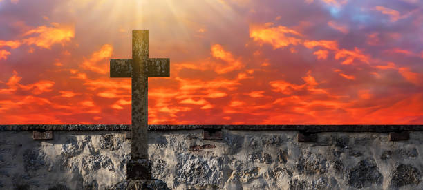 « nseuissement religieux - vieille croix de pierre et vieux mur de briques dans le cimetière au coucher du soleil - good friday photos et images de collection