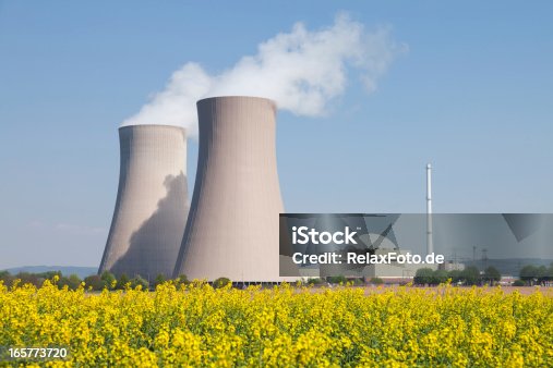 istock Nuclear power station with steaming cooling towers and canola field 165773720