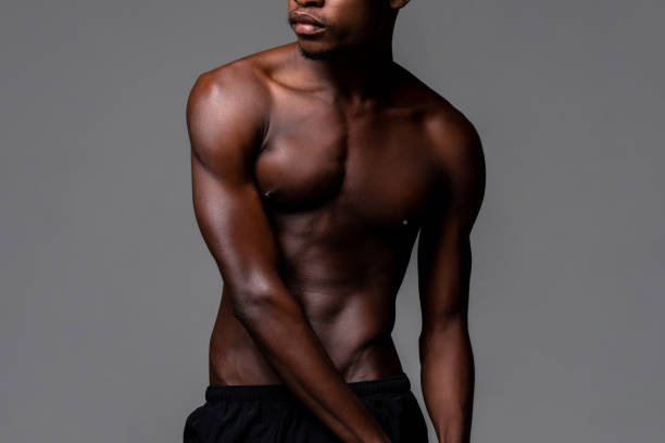 Nude lean young African man body in studio isolated gray background stock photo