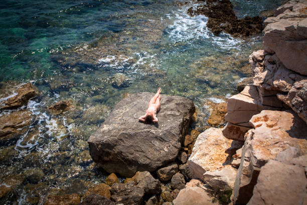 Nude woman on rocky beach stock photo