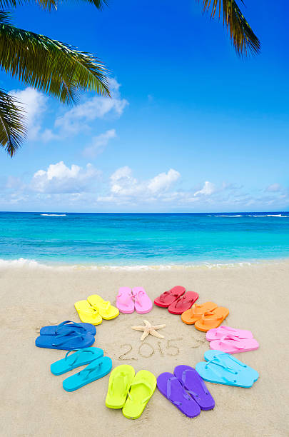 Number 2015 with color flip flops and starfish on the sandy beach -...