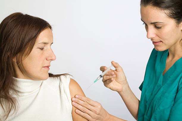 Nurse administrating injection to woman patient stock photo