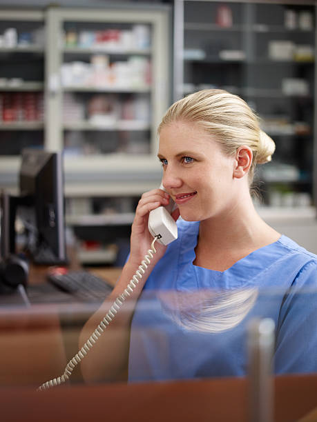 nurse at hospital front desk taking a phone call - happy scrubs nurse phone bildbanksfoton och bilder